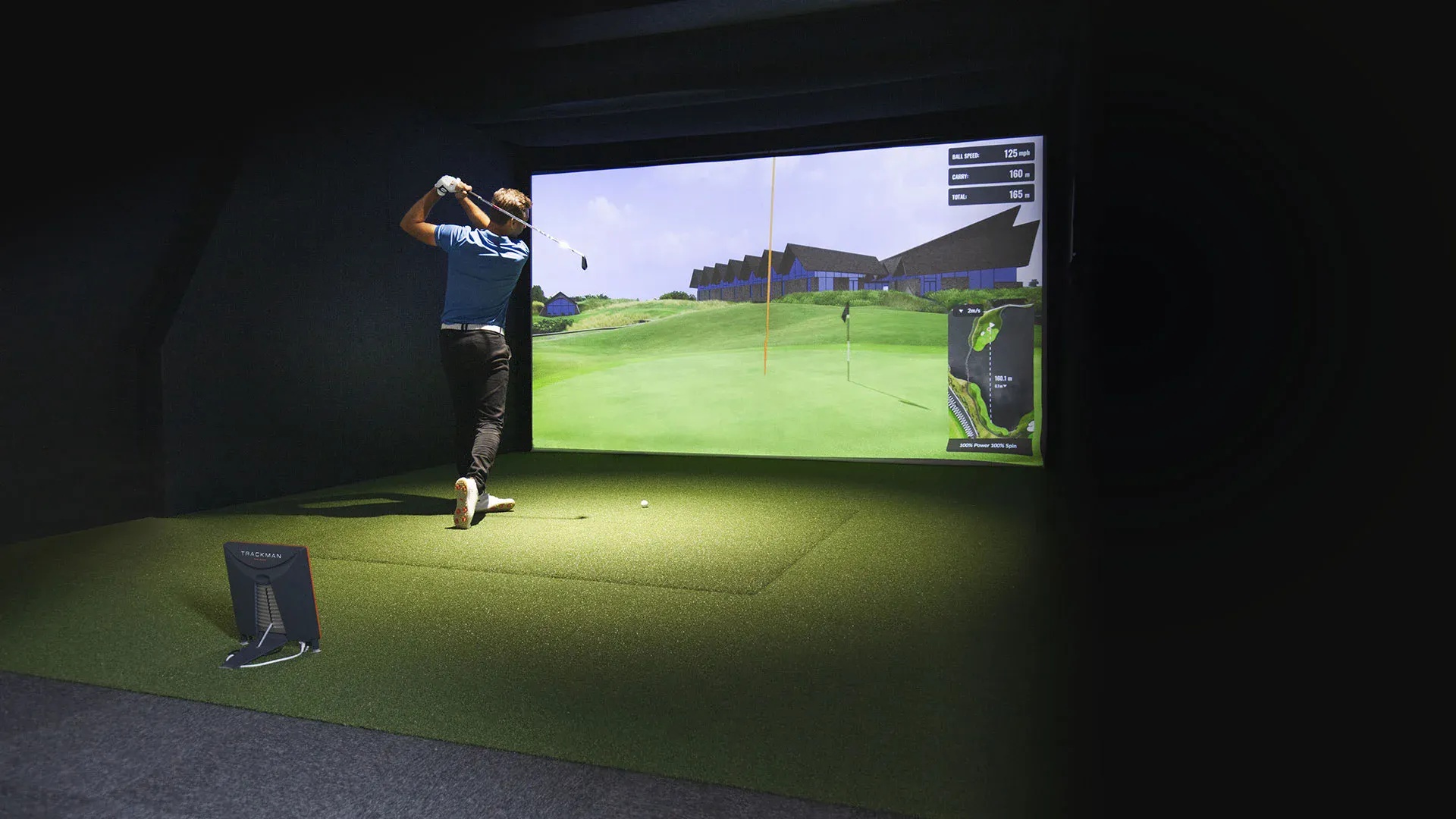 A golfer taking a swing in a TrackMan simulator bay at APEX Swing Academy
