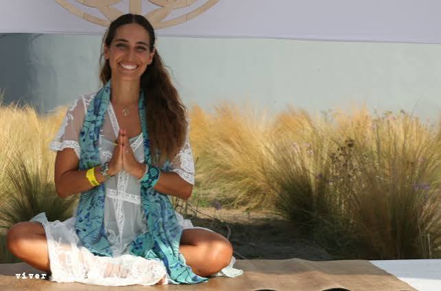 Isa Guitana seated in prayer hands on a mat outdoors