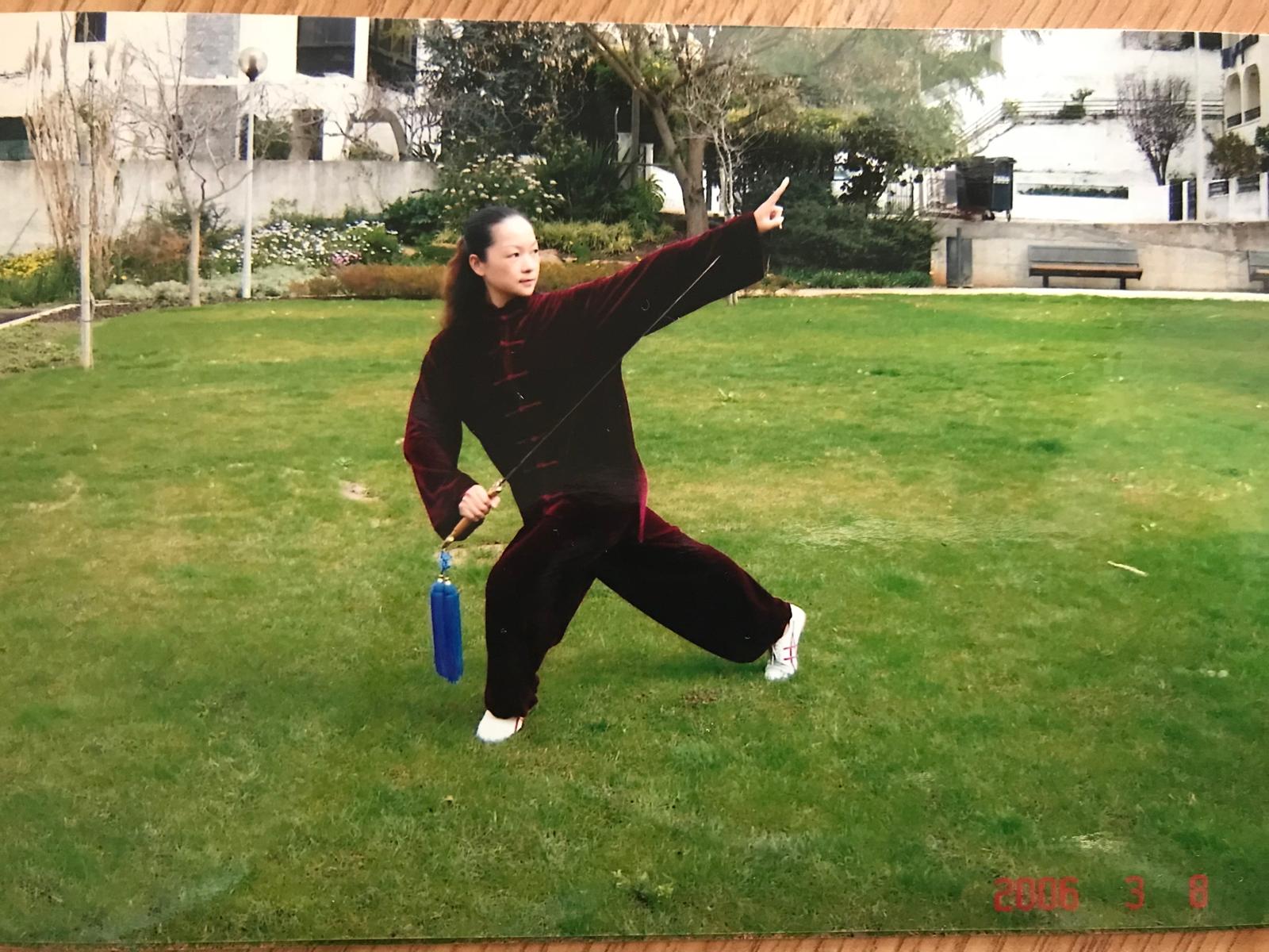 Instructor in a balanced stance with a Tai Chi sword and blue tassel